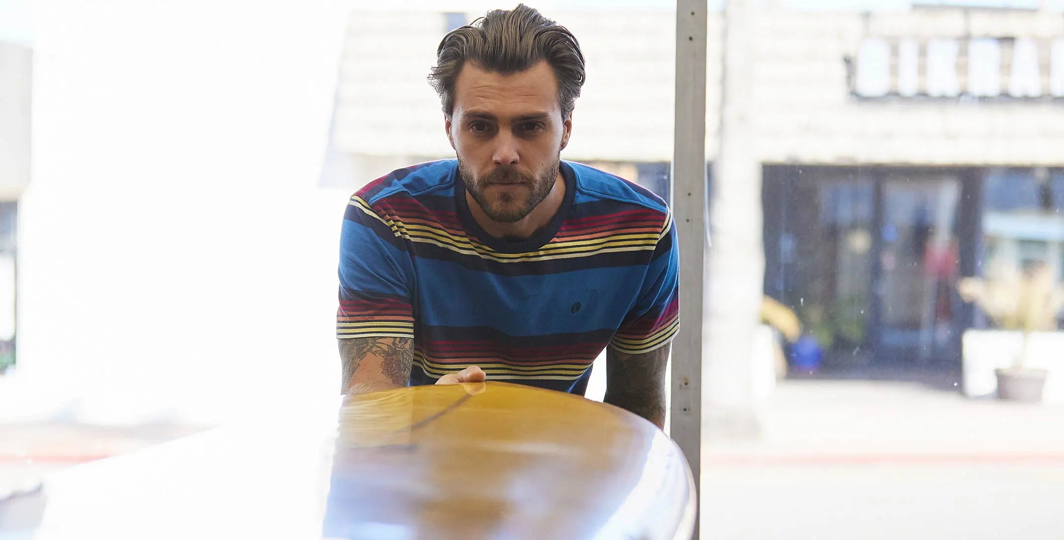 Man in a striped shirt leaning over a counter in a modern kitchen.